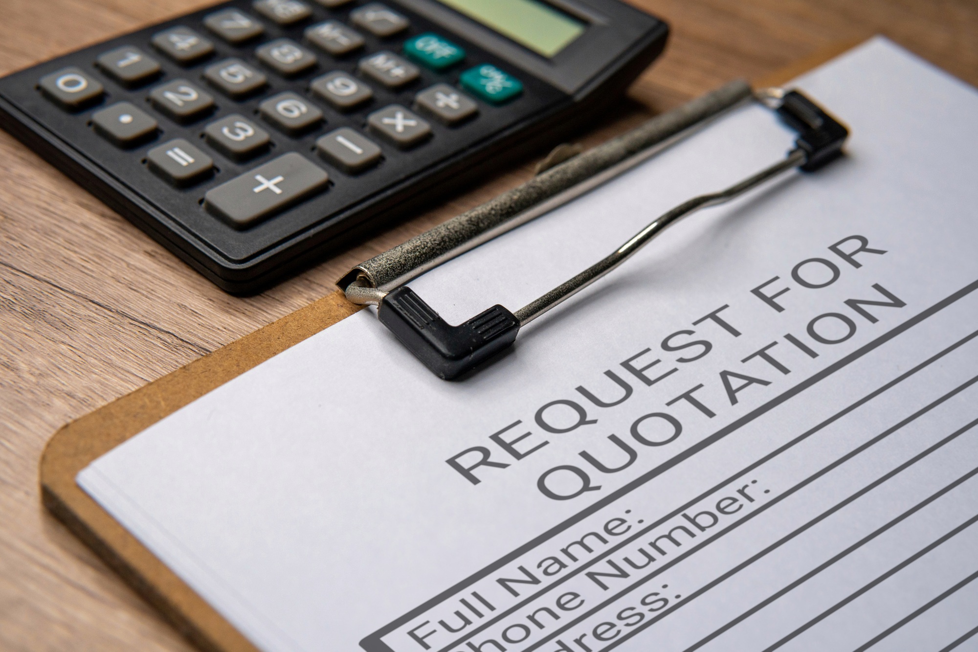 A clipboard with a paper titled “REQUEST FOR QUOTATION” and a black calculator.