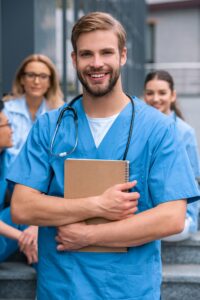 handsome caucasian medical student standing with notebook and looking at camera