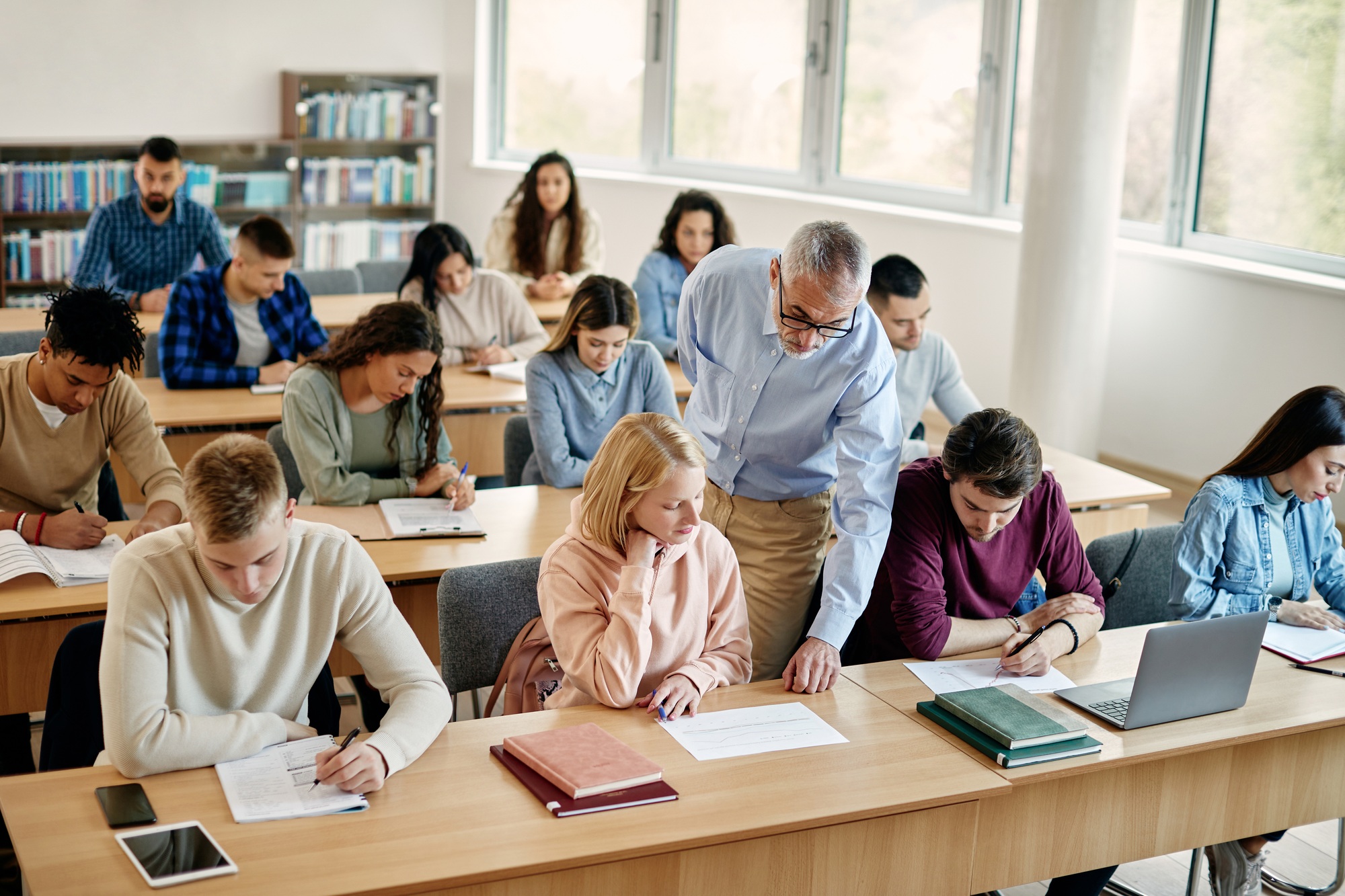 Senior teacher assisting his students during a class at lecture hall.